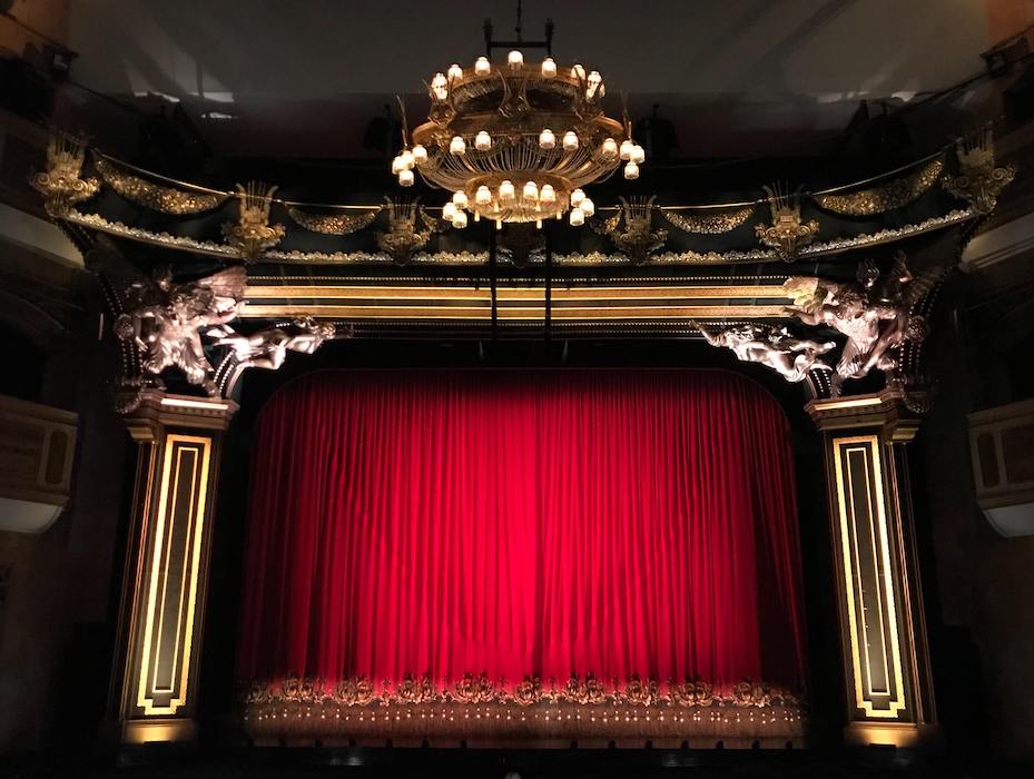 View of theatre stage with traditional red curtain hanging down