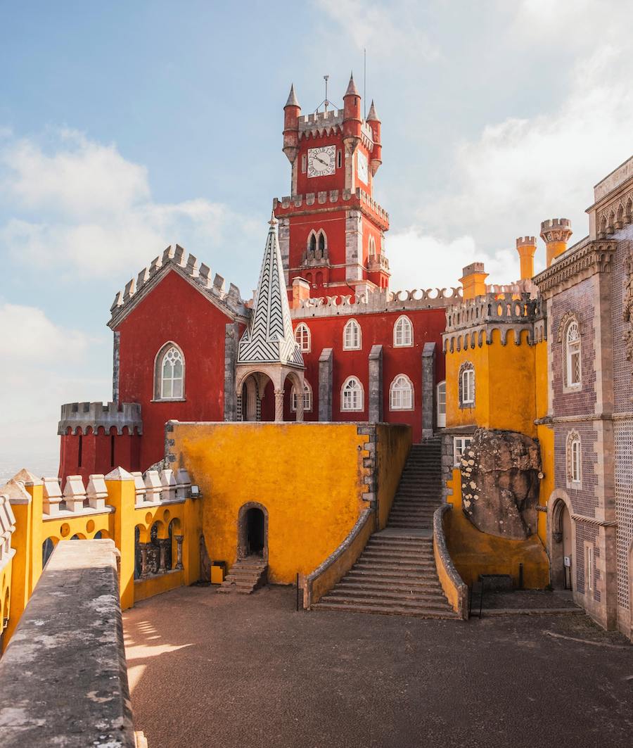 Pena Palace in Portugal — a bright yellow and red painted castle on top of a hill