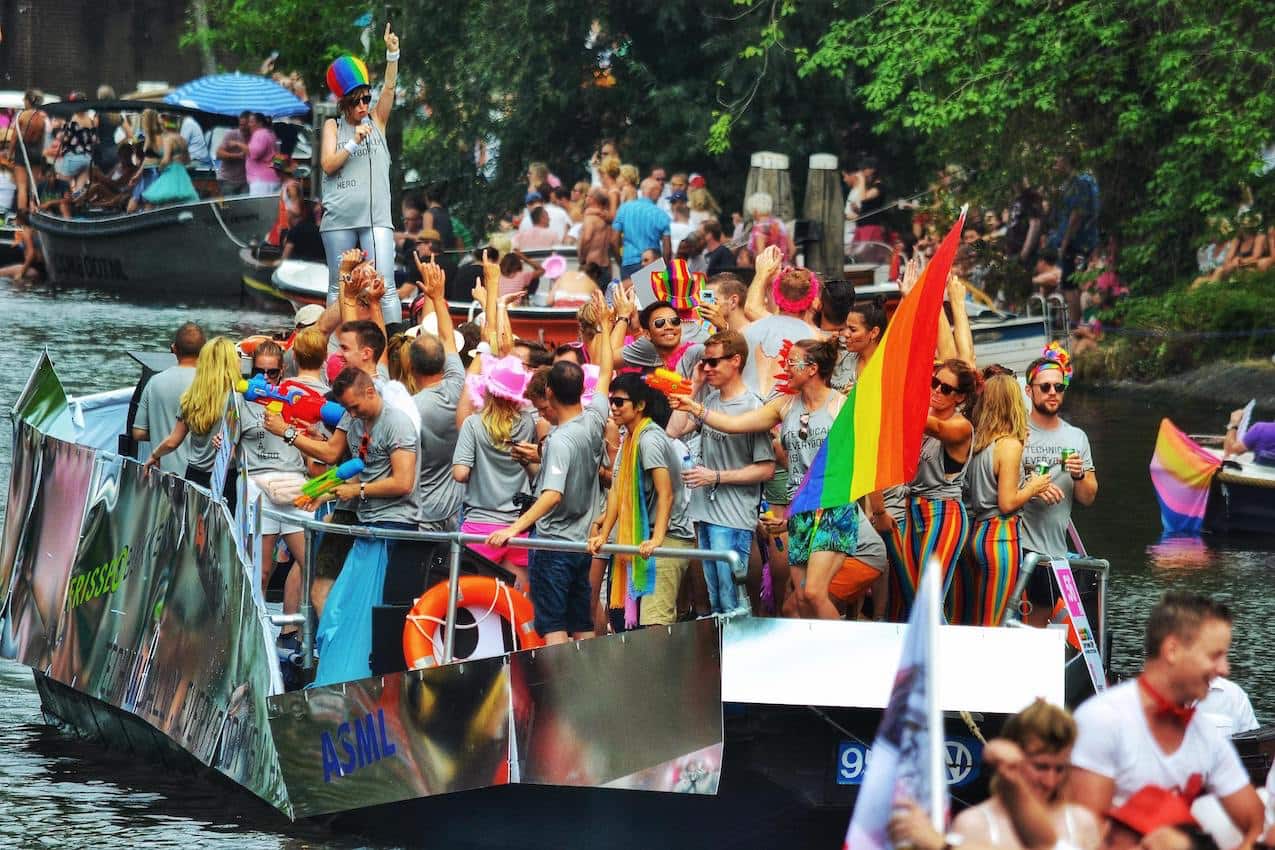 dozens of young people celebrating Gay Pride with rainbow flags and colourful clothes