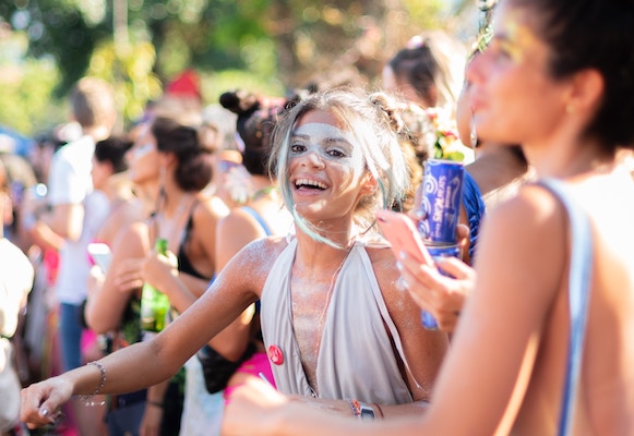 girl with silver face paint and dress smiling at a sunny festival