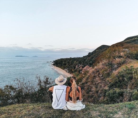 influencer couple overlooking beach from grassy hilltop